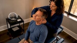 Chiropractor adjusting patient with neurofeedback equipment nearby