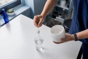 Hands pouring creatine powder into glass