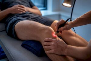 Clinician applying cold laser to knee