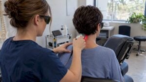 Clinician applying laser therapy to patient’s neck